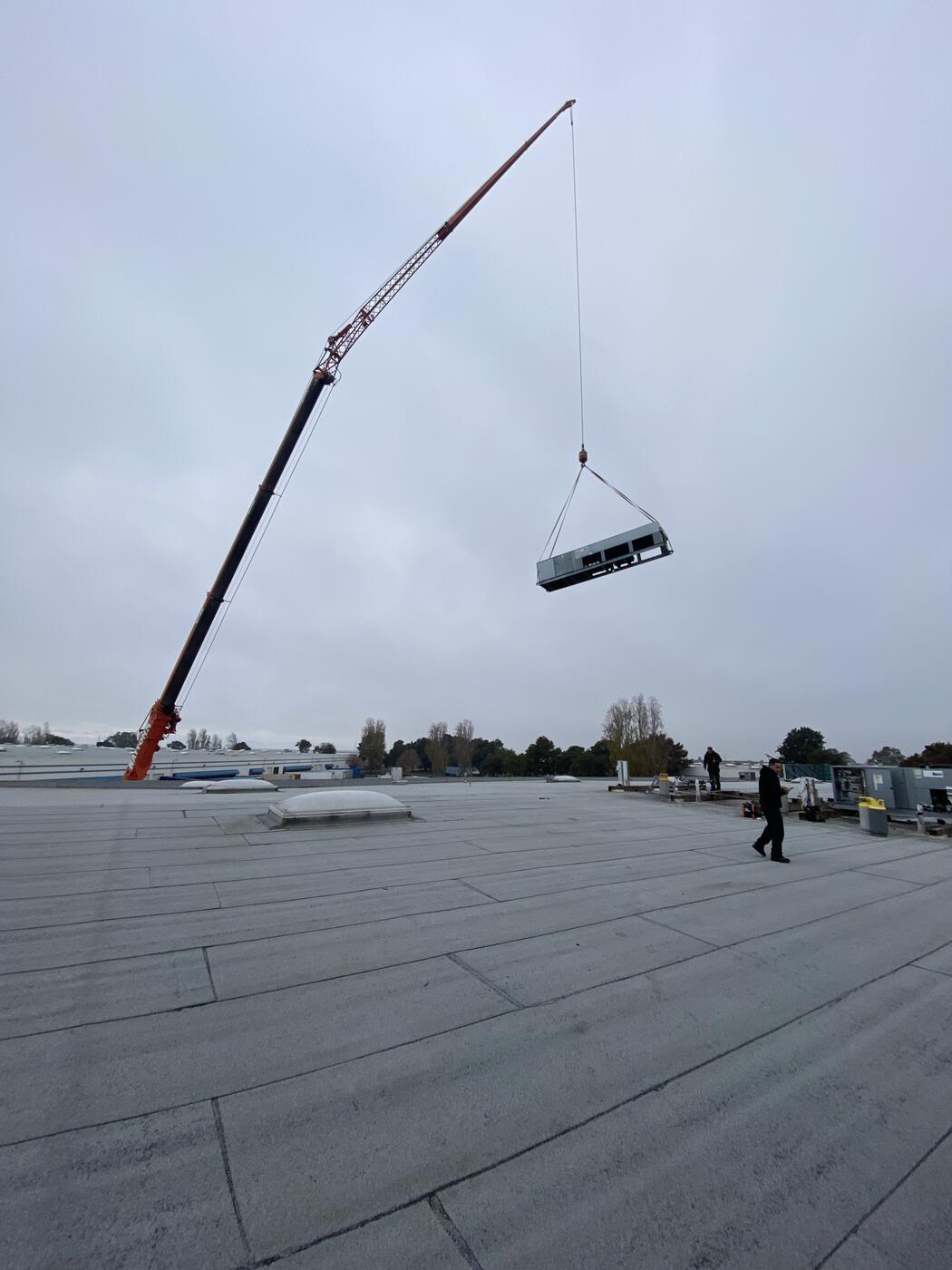 Crane lifting refrigeration equipment to rooftop